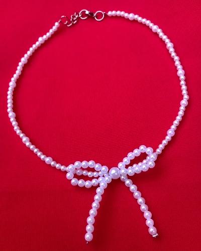 Colgante tipo chocker de perlas con moño.